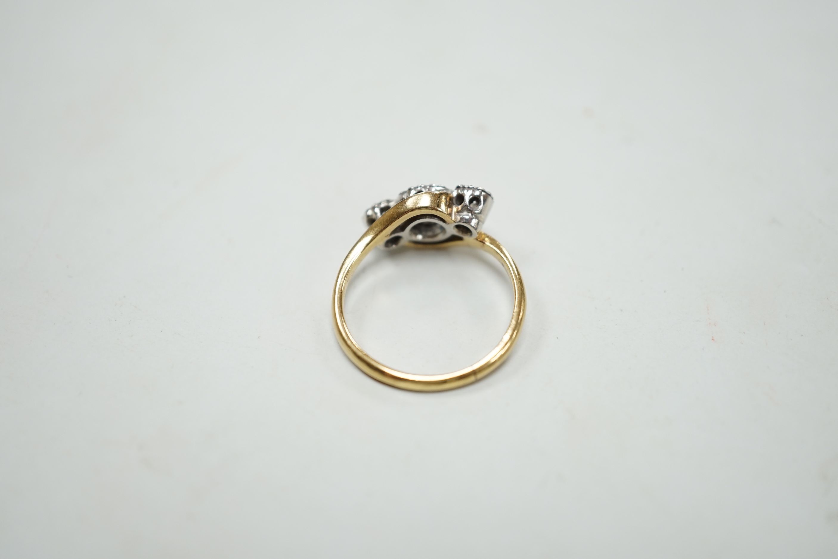 An 18ct and illusion set three stone diamond crossover ring, size I, gross weight 2.5 grams.